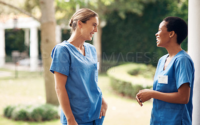 Buy stock photo Shot of two young nurses talking outside in the garden of a retirement home