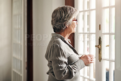 Buy stock photo Shot of a senior woman having coffee and looking thoughtfully out of a window