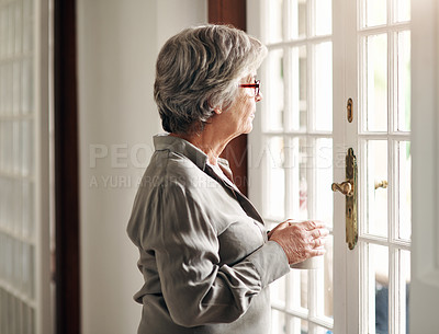 Buy stock photo Shot of a senior woman having coffee and looking thoughtfully out of a window