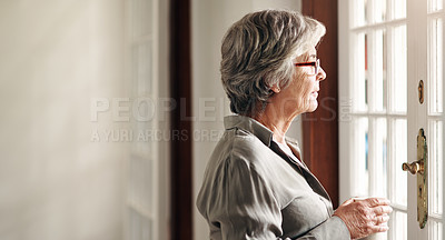 Buy stock photo Shot of a senior woman having coffee and looking thoughtfully out of a window