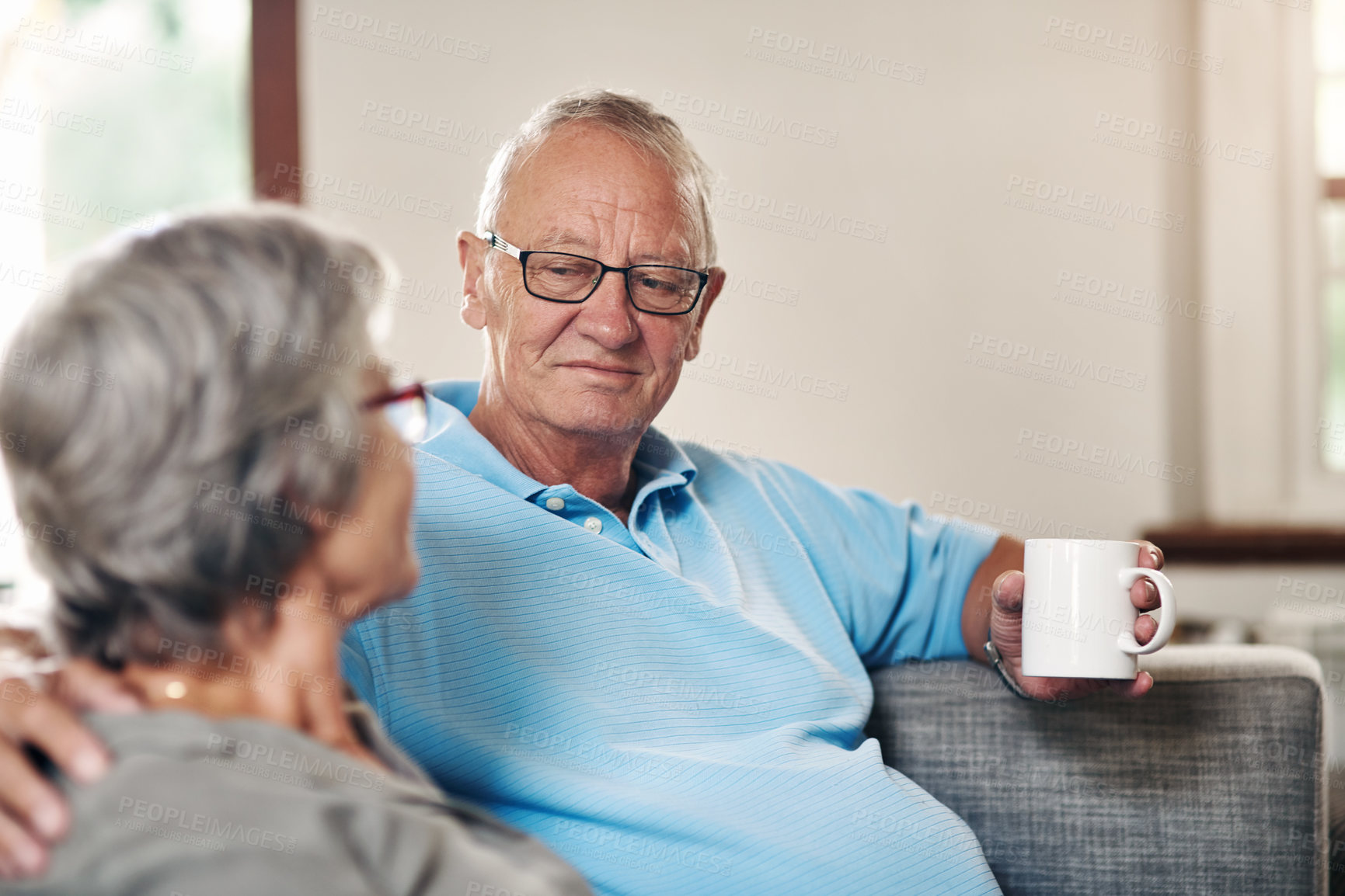 Buy stock photo Shot of a senior couple enjoying a coffee break while relaxing together on the sofa at home