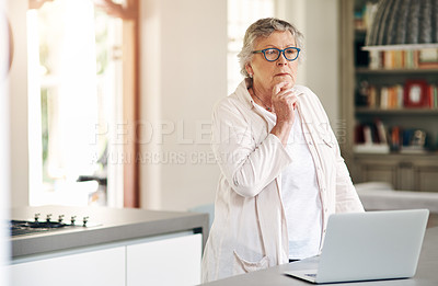 Buy stock photo Shot of a senior woman looking thoughtful while using a laptop at home