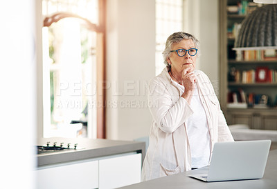 Buy stock photo Shot of a senior woman looking thoughtful while using a laptop at home