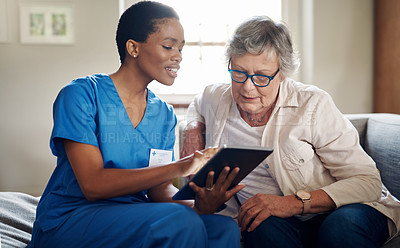 Buy stock photo Shot of a senior woman using a digital tablet with a nurse on the sofa at home