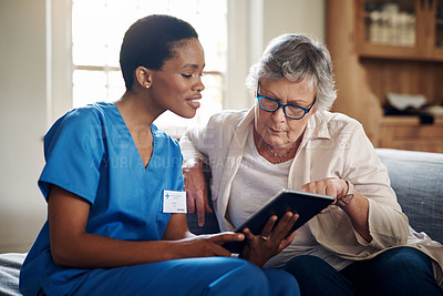 Buy stock photo Shot of a senior woman using a digital tablet with a nurse on the sofa at home