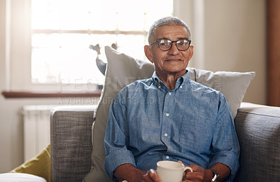 Buy stock photo Shot of a senior man having a coffee break on the sofa at home