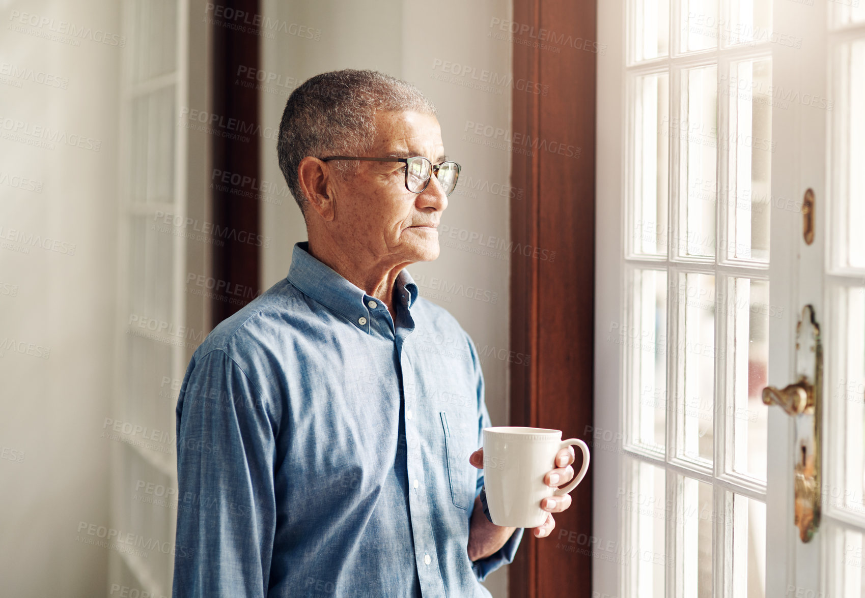 Buy stock photo Shot of a senior man having coffee and looking thoughtfully out of a window