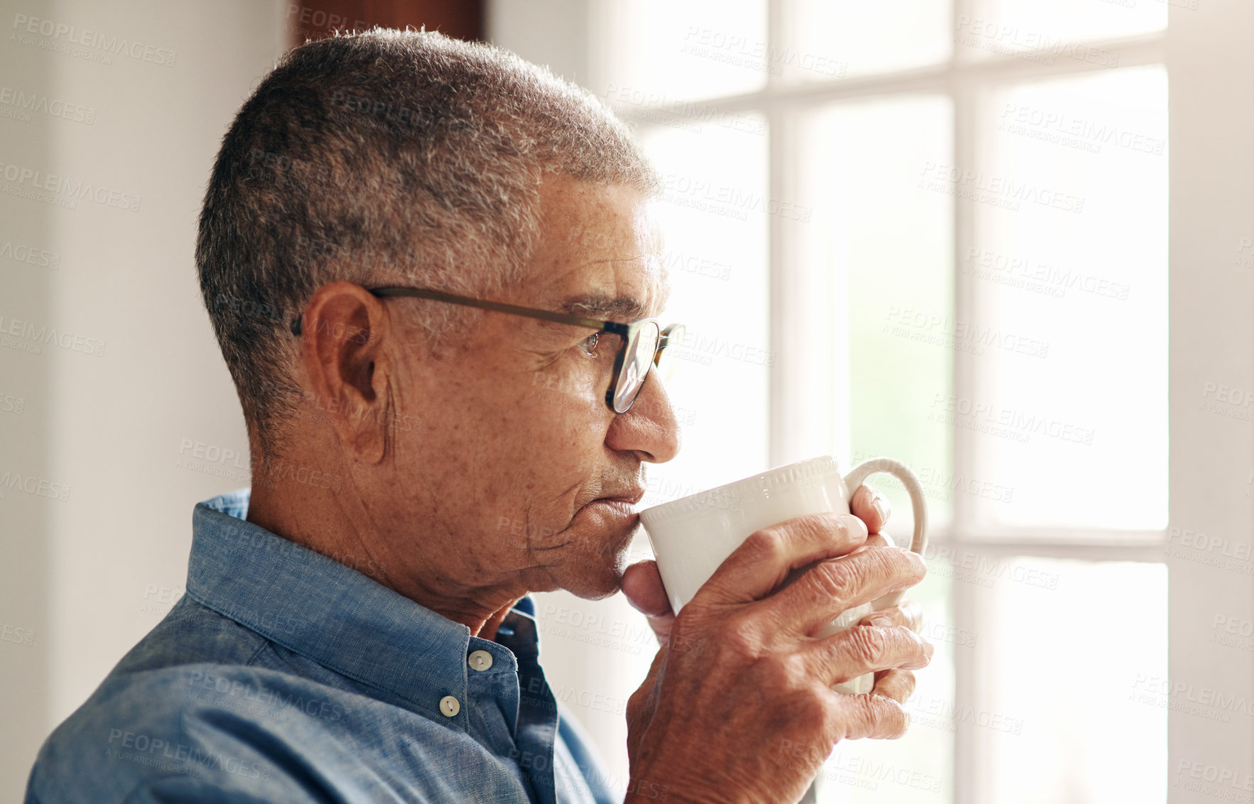 Buy stock photo Shot of a senior man having coffee and looking thoughtfully out of a window