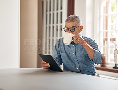 Buy stock photo Shot of a senior man having coffee and using a digital tablet at home