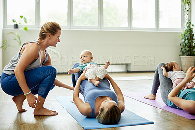 Buy stock photo Cropped shot of a young group of mothers lying down and posing with her babies during a baby yoga class