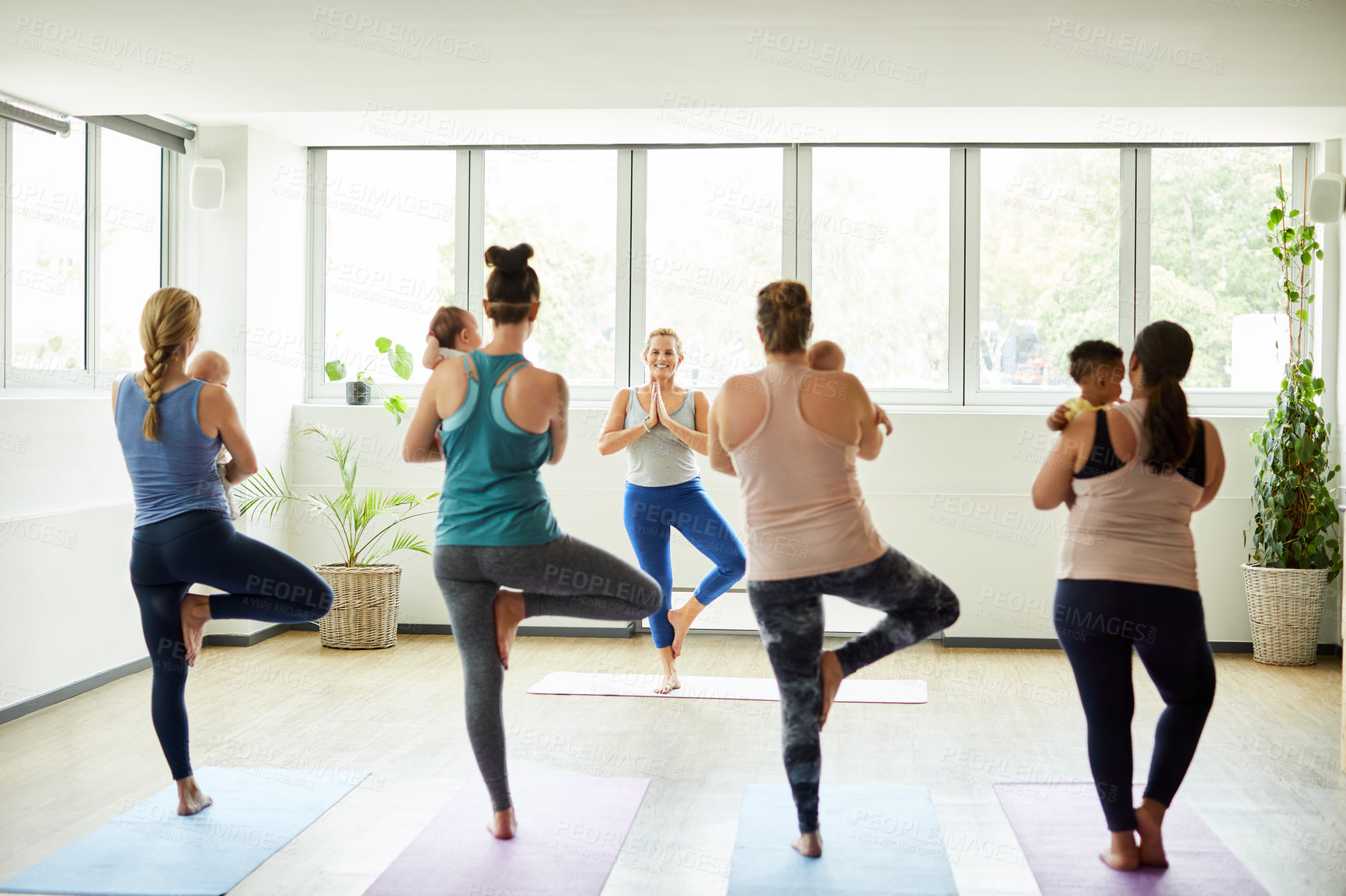 Buy stock photo Full length shot of a group of mothers holding their babies during a baby yoga class indoors