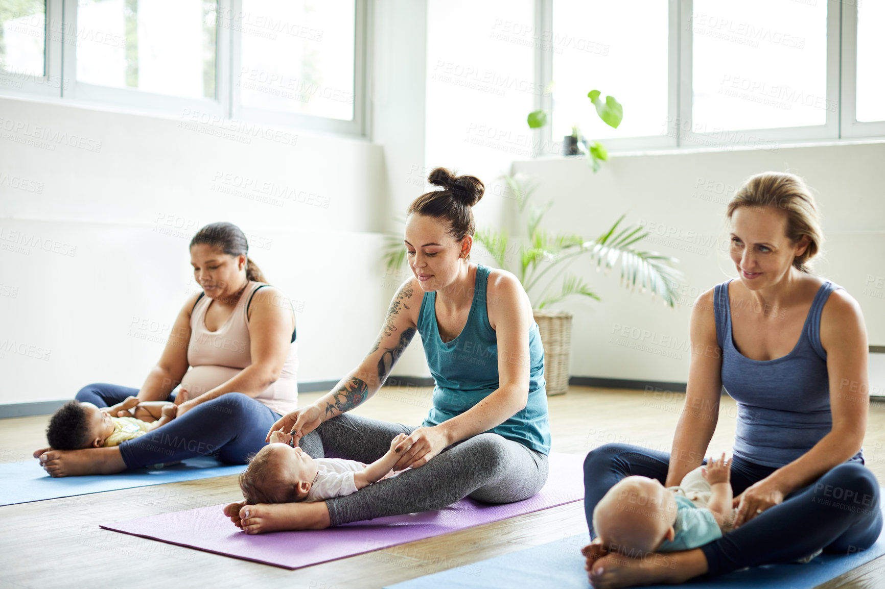 Buy stock photo Full length shot of a young group of mothers sitting with their babies during a baby yoga class indoors
