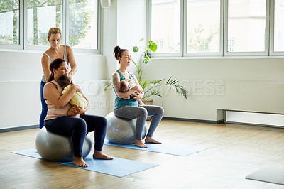 Buy stock photo Full length shot of two attractive young mothers sitting with their babies during a baby yoga class indoors