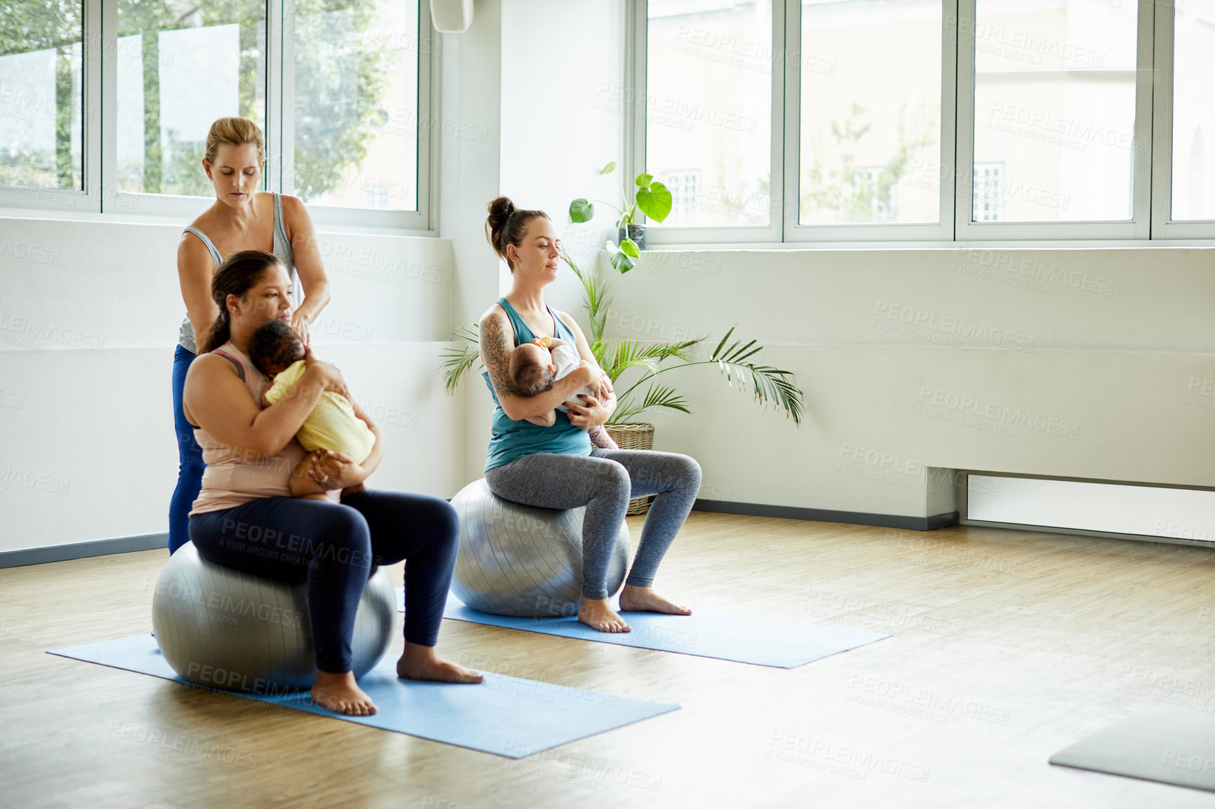 Buy stock photo Full length shot of two attractive young mothers sitting with their babies during a baby yoga class indoors