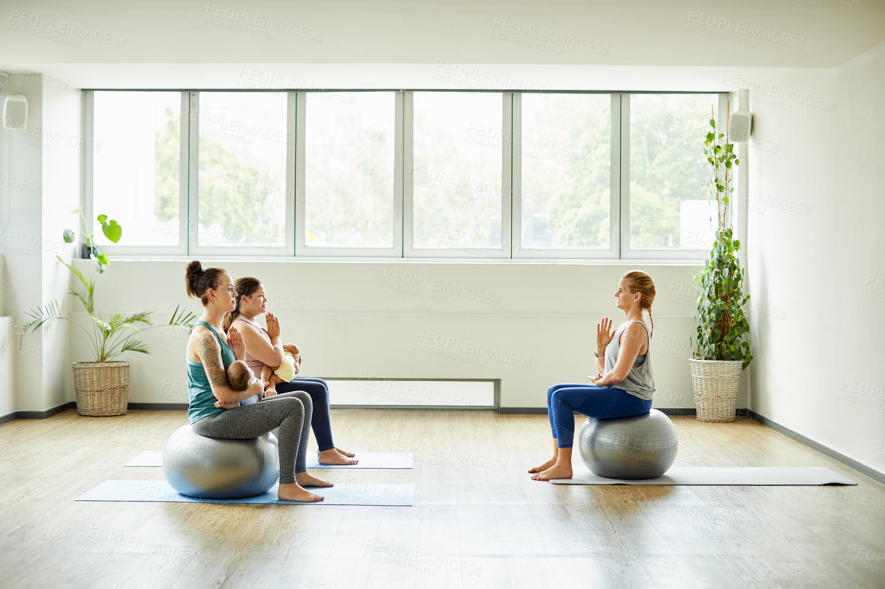 Buy stock photo Full length shot of two attractive young mothers sitting with their babies during a baby yoga class indoors