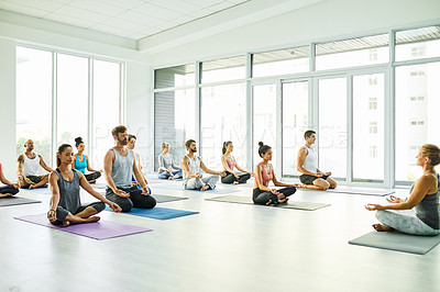 Buy stock photo Shot of a group of men and women meditating in the lotus position during a yoga class