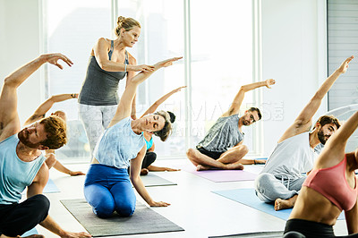 Buy stock photo Shot of a group of men and women practicing yoga in a fitness class