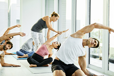 Buy stock photo Shot of a group of men and women practicing yoga in a fitness class