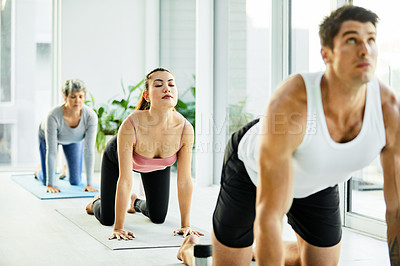 Buy stock photo Shot of a group of men and women practicing yoga in a fitness class
