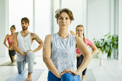 Buy stock photo Shot of a group of men and women practicing yoga in a fitness class