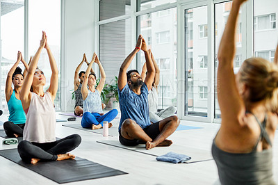 Buy stock photo Shot of a group of men and women practicing yoga in a fitness class