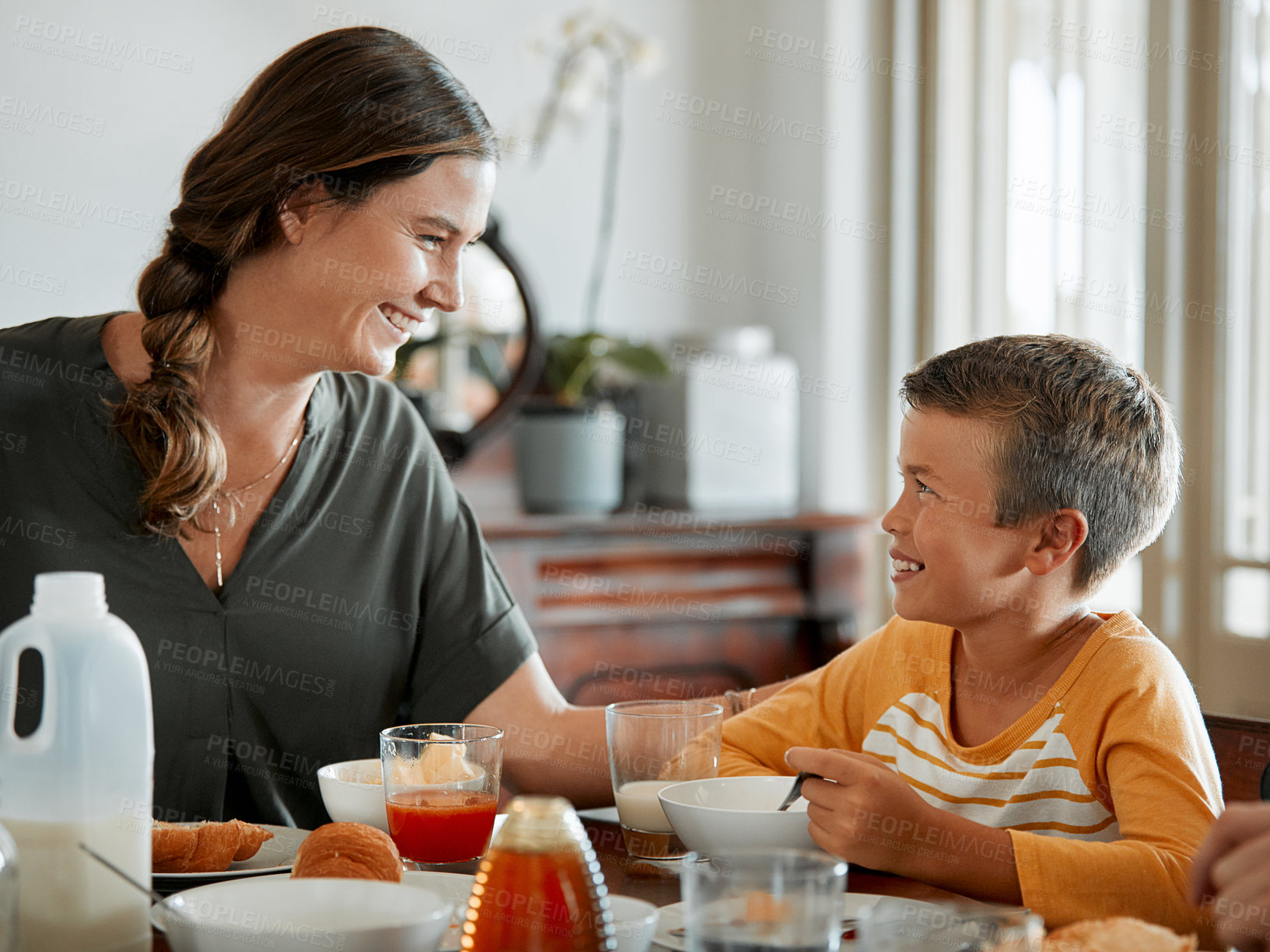 Buy stock photo Care, mother and eating breakfast with happy child in home, growth and development with nutrition. Morning meal, parent and hungry boy with smile for family wellness, food and healthy diet for love