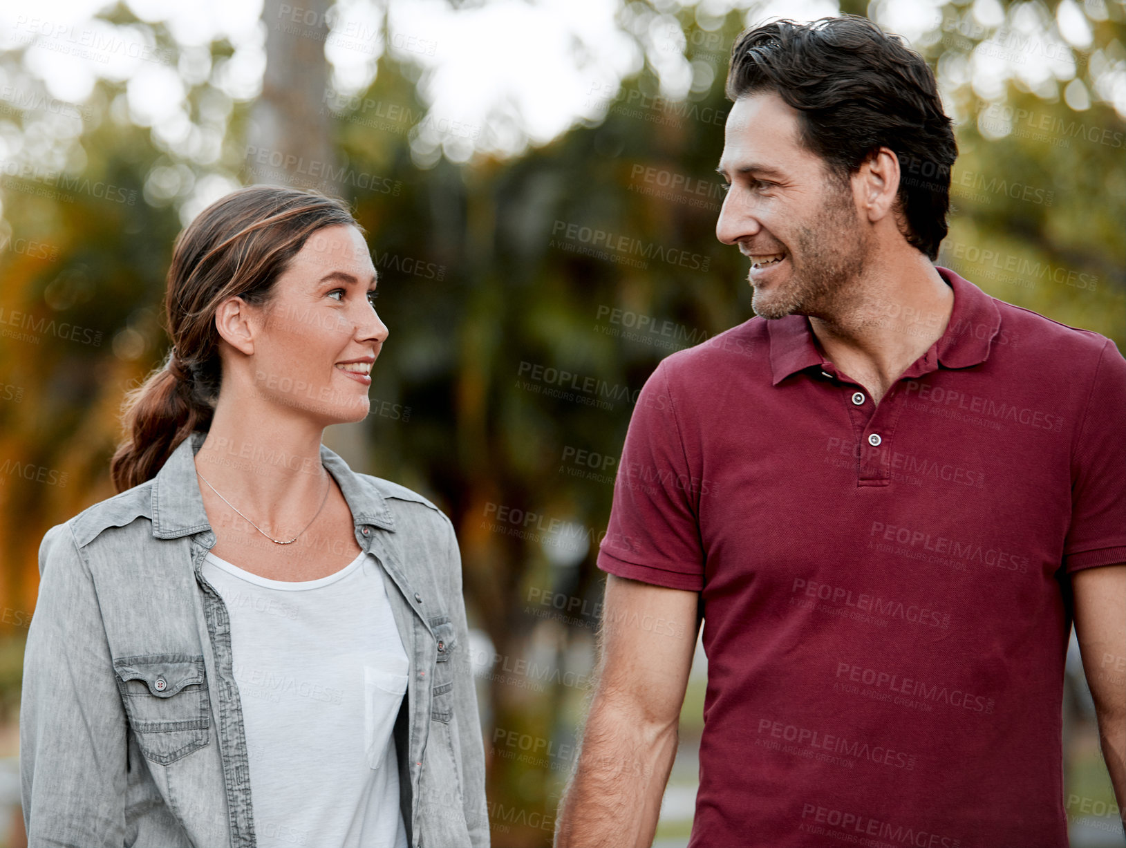 Buy stock photo Cropped shot of an affectionate couple taking a walk through the park
