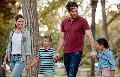 Buy stock photo Shot of a couple with two kids taking a walk through the park together
