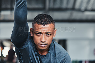 Buy stock photo Cropped portrait of a handsome young male athlete going through his warmup routine in the gym