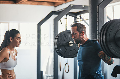 Buy stock photo Shot of a man working out with the help of his coach at the gym