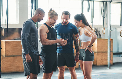 Buy stock photo Cropped shot of a group of young athletes looking at a cellphone while standing in the gym