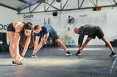 Buy stock photo Full length shot of a group of young athletes going through their warmup routine in the gym