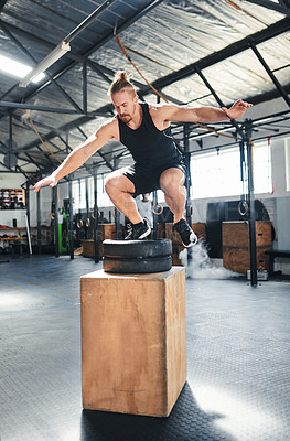 Buy stock photo Shot of a fit young man doing box jumps at the gym