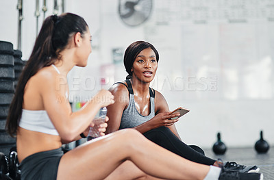 Buy stock photo Shot of two young women talking while sitting together at the gym