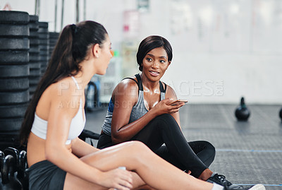 Buy stock photo Shot of two young women talking while sitting together at the gym