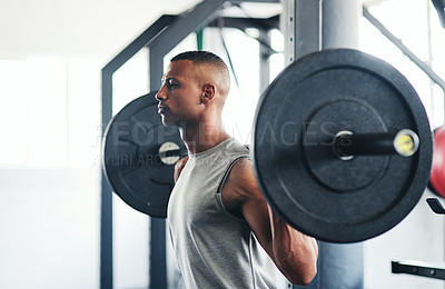 Buy stock photo Cropped shot of a young man working out with a barbell at the gym