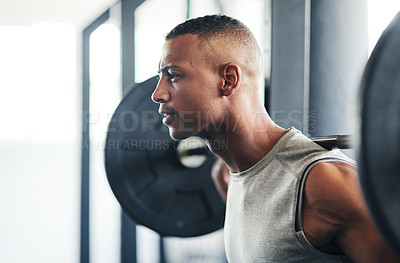 Buy stock photo Cropped shot of a young man working out with a barbell at the gym