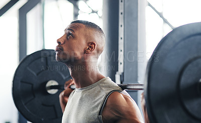 Buy stock photo Cropped shot of a young man working out with a barbell at the gym