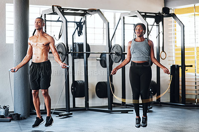Buy stock photo Shot of two young athletes using skipping ropes while working out at the gym