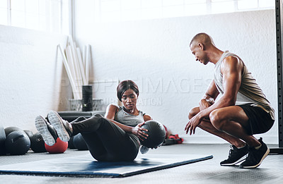 Buy stock photo Shot of a woman working out with the help of her coach at the gym