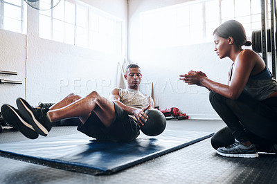 Buy stock photo Shot of a man working out with the help of his coach at the gym