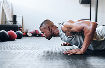 Buy stock photo Cropped shot of a fit young man doing pushups at the gym