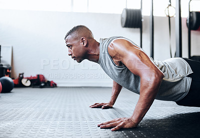 Buy stock photo Cropped shot of a fit young man doing pushups at the gym