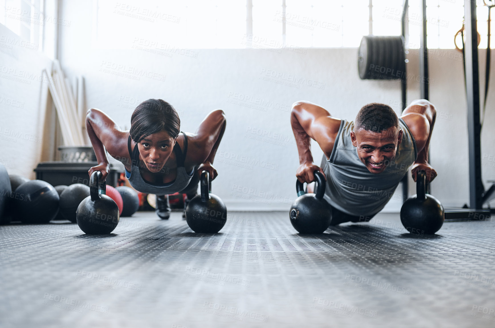 Buy stock photo Shot of two young athletes working out using kettle bells at the gym