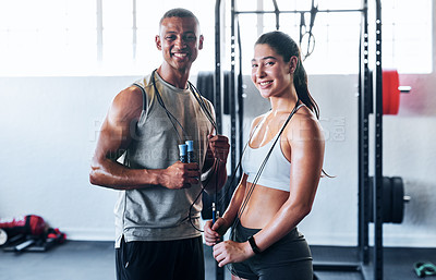 Buy stock photo Portrait shot of two young athletes using skipping ropes while working out at the gym