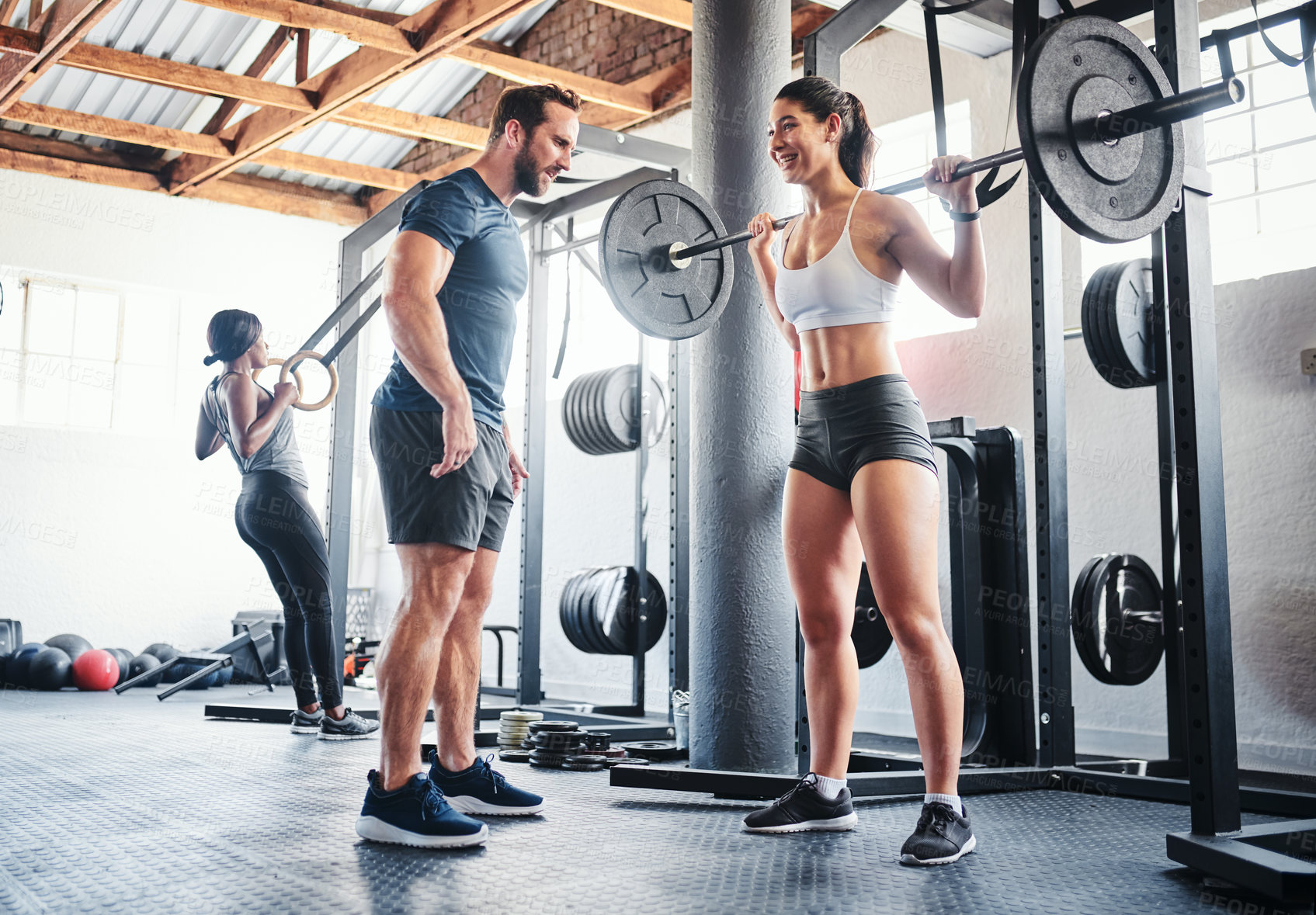 Buy stock photo Shot of a woman working out with the help of her coach at the gym