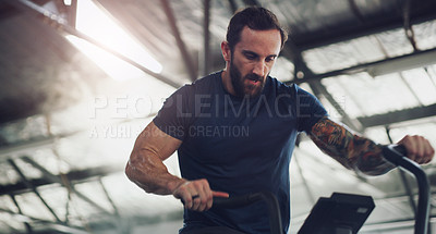 Buy stock photo Shot of a young man working out on an exercise bike in a gym
