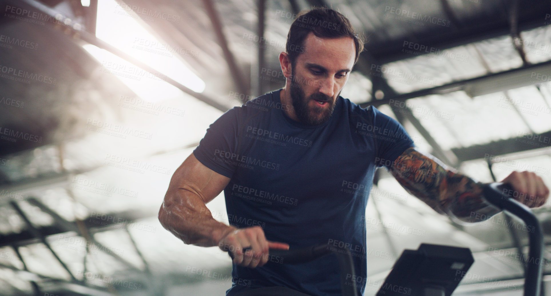 Buy stock photo Intense, workout and stationary bike with man in gym for cardio machine, health and fitness. Training equipment, cycling and exercise with person in sports club for performance, wellness and energy