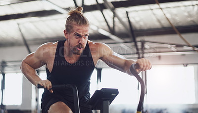 Buy stock photo Shot of a young man working out on an exercise bike in a gym