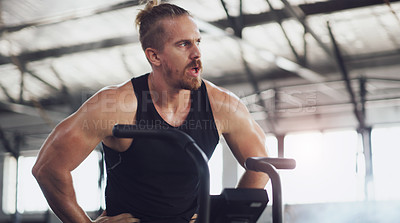 Buy stock photo Shot of a young man taking a break while working out on an exercise bike in a gym